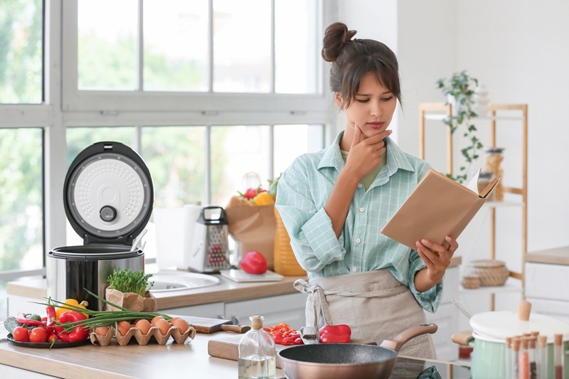 אישה במטבח מעיינת בספר בישול